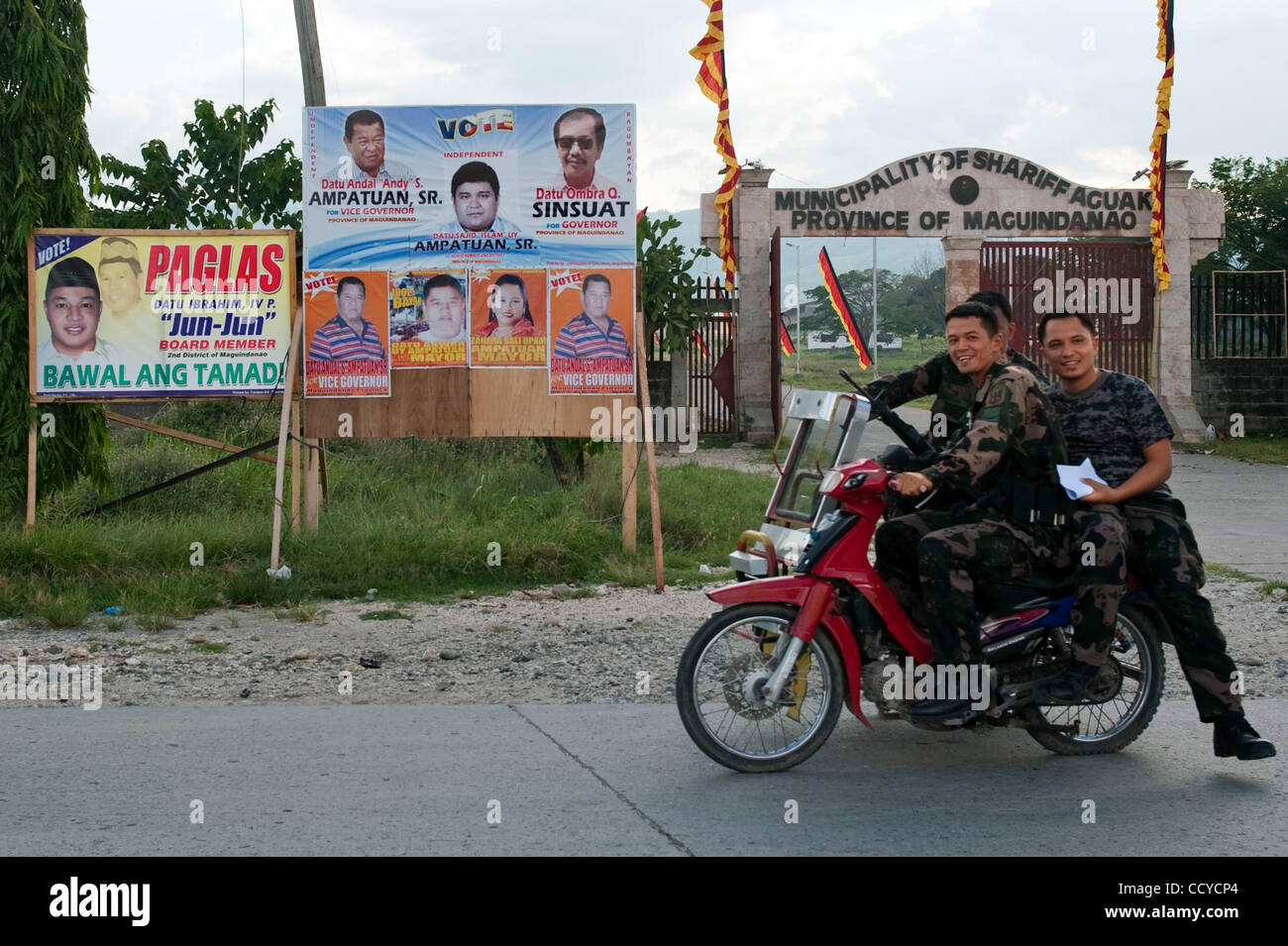 03 mai 2010 - Shariff Aguak, Mindanao, Philippines - Des soldats sur la moto passer par des affiches électorales le 03 mai 2010 à Shariff Aguak, Maguindanao Philippines..les Forces armées des Philippines (AFP) sont en alerte rouge comme les élections aux Philippines sont accompagnés d'une montée de la violence comme politici Banque D'Images