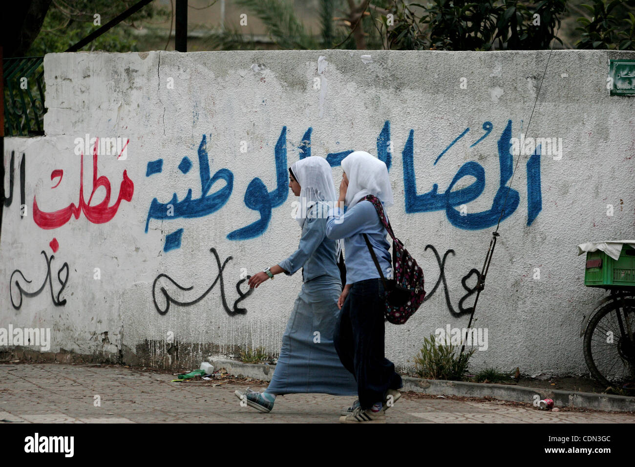 Girlschool palestiniens à pied passé lecture graffiti en arabe, "Oui à la fin de la division", dans la ville de Gaza le 28 avril 2011, alors que les Palestiniens dans la bande de Gaza et la Cisjordanie s'est félicité des rapports qui leur rival factions au pouvoir le Hamas et le Fatah avait atteint un accord de réconciliation politique dans Banque D'Images