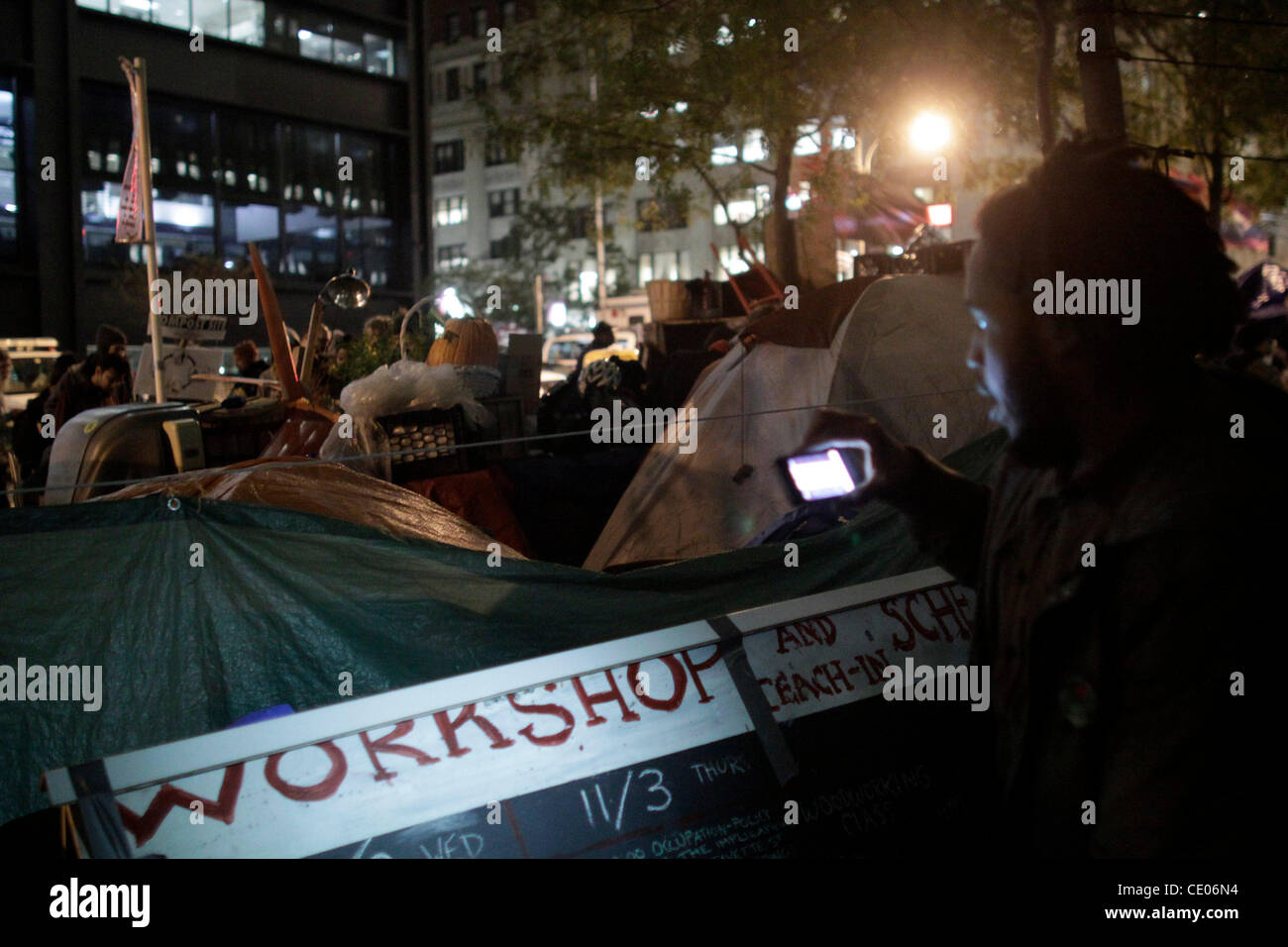 Occupy Wall Street et à enseigner dans l'atelier Annexe éclairé avec un smartphone dans Zuccotti Park. Banque D'Images