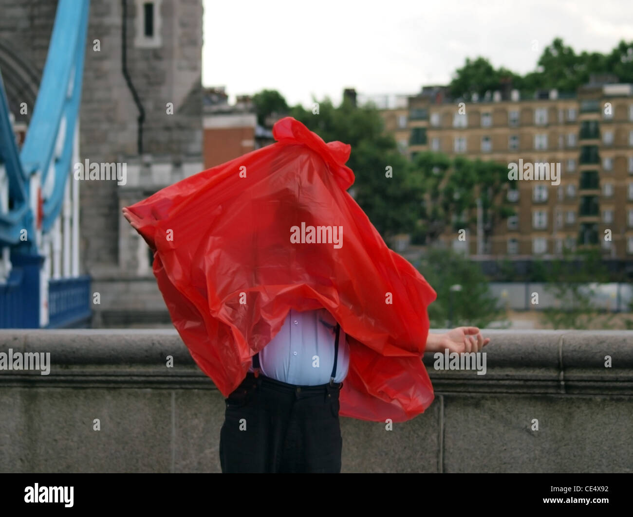 Un touriste se fait tout embrouillé vers le haut pendant une averse soudaine sur le Tower Bridge de Londres Banque D'Images