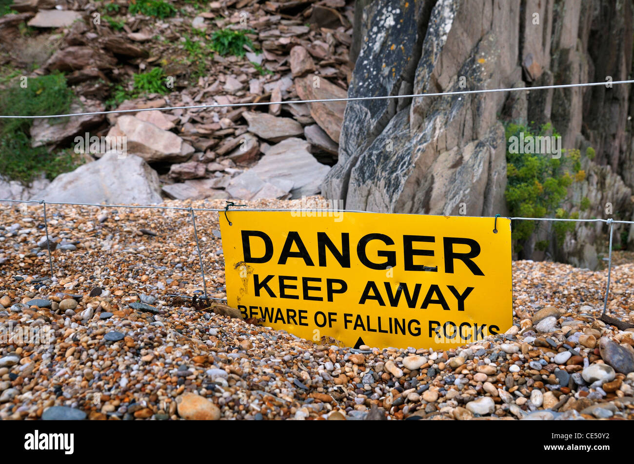 Le signe de danger sur la plage les informant des chutes de pierres Banque D'Images
