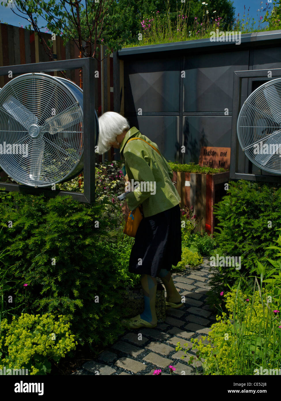 Un visiteur se penche en avant pour regarder les plantes dans le jardin de Chelsea vents du changement Banque D'Images