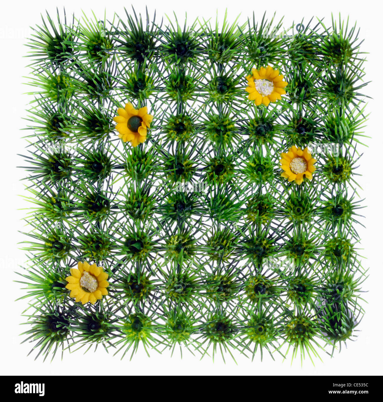 Gazon artificiel, quadratique, prairie, avec des fleurs en plastique jaune. La décoration. Banque D'Images