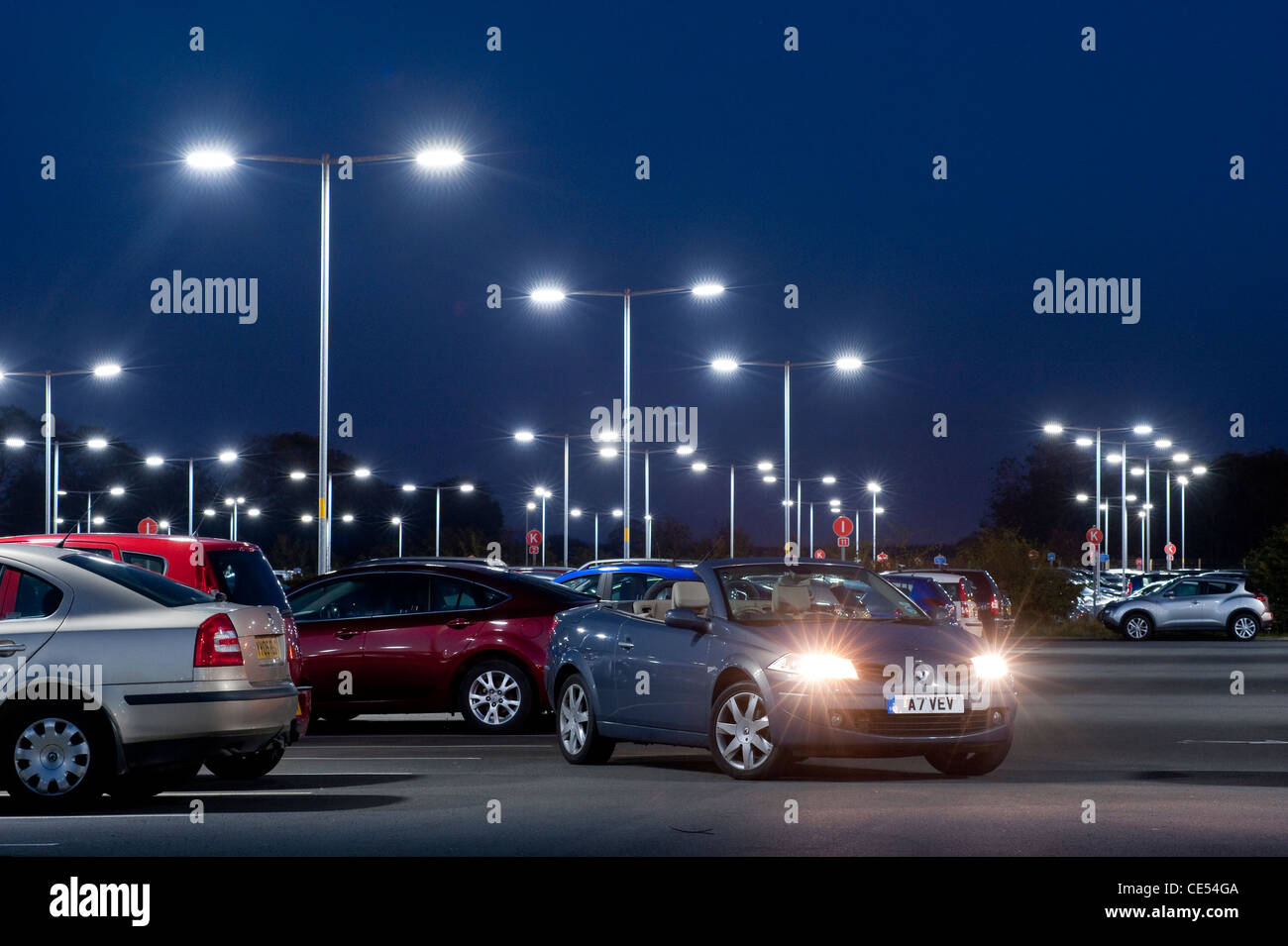 Renault Megane coupé cabriolet voiture avec les véhicules garés dans un parking très occupé au crépuscule en Angleterre. Banque D'Images