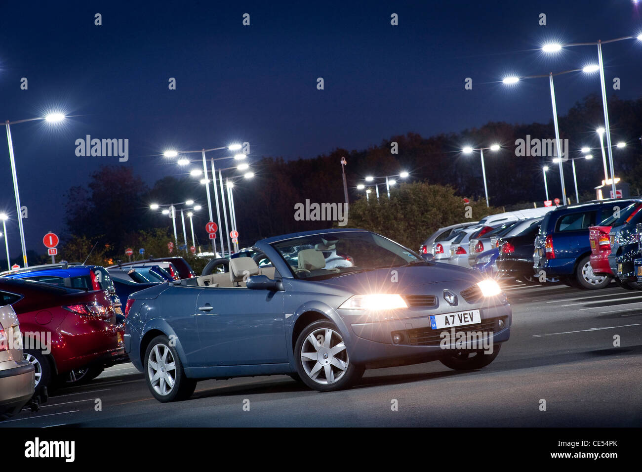Renault Megane coupé cabriolet voiture avec les véhicules garés dans un parking très occupé au crépuscule en Angleterre. Banque D'Images