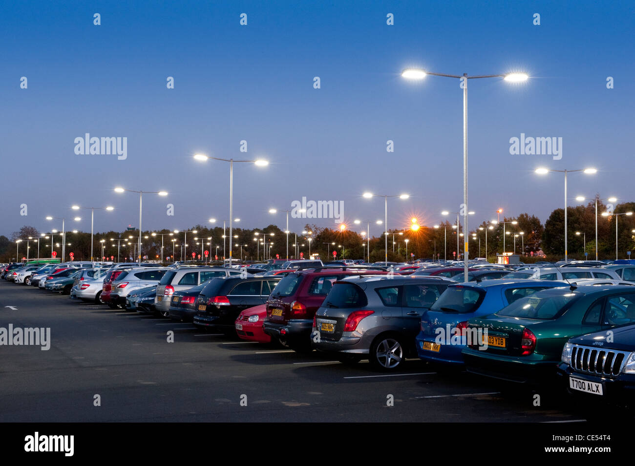 Les véhicules garés dans un parking aéroport très fréquenté au crépuscule en Angleterre. Banque D'Images