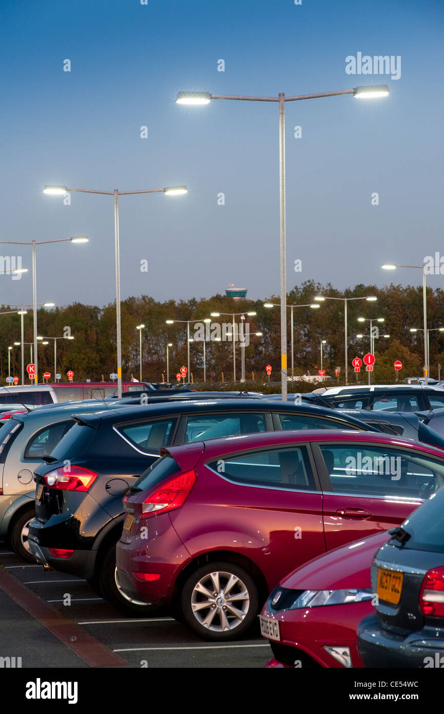 Les véhicules garés dans un parking aéroport très fréquenté au crépuscule en Angleterre. Banque D'Images