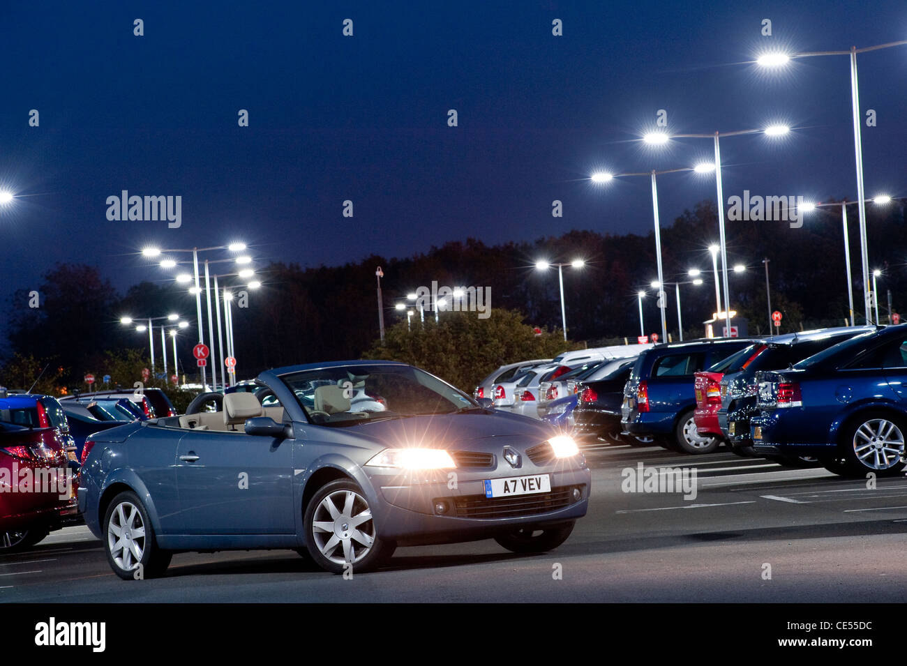 Renault Megane coupé cabriolet avec des véhicules garés dans un parking très occupé au crépuscule en Angleterre. Banque D'Images