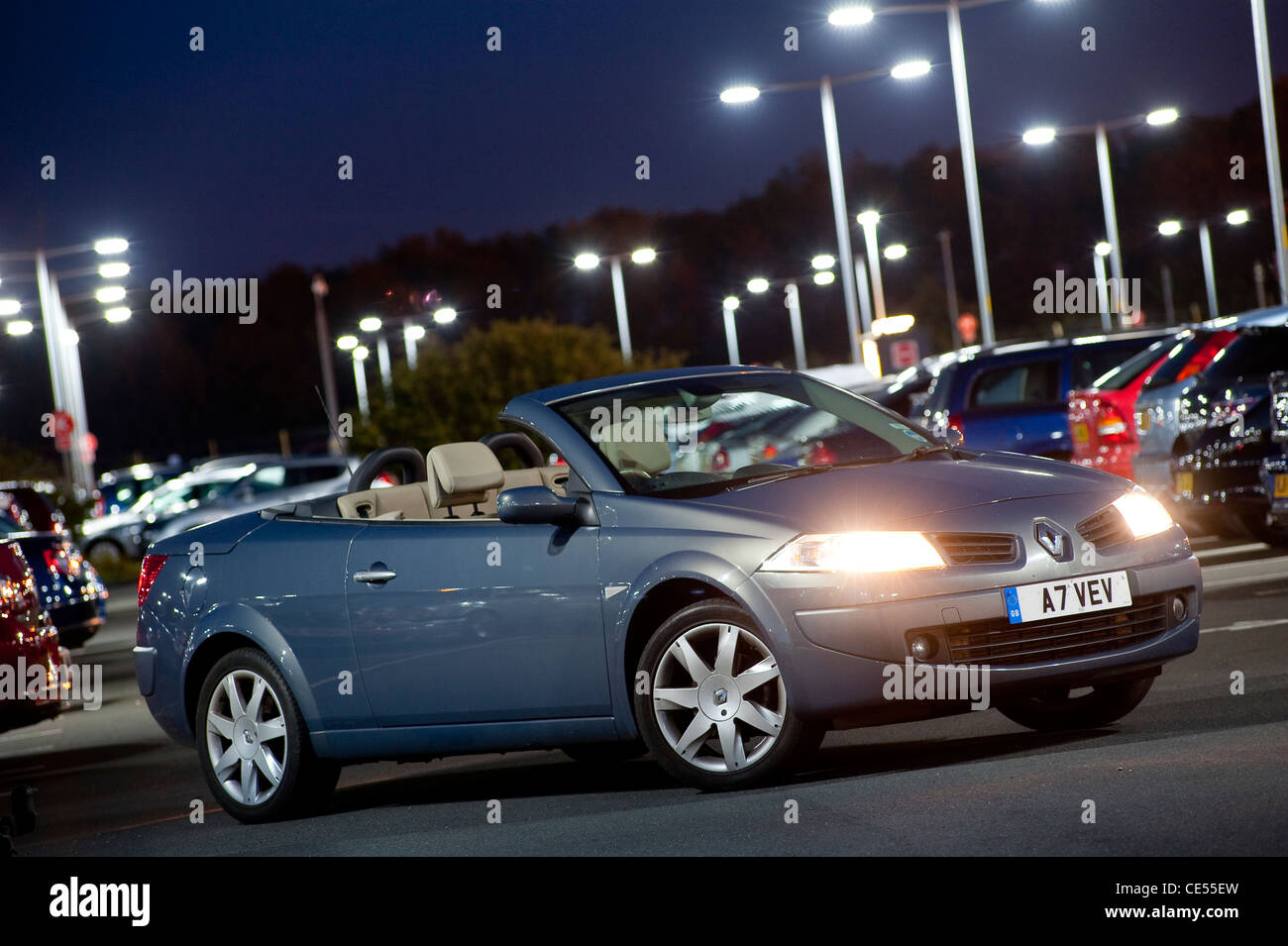 Renault Megane coupé cabriolet avec des véhicules garés dans un parking très occupé au crépuscule en Angleterre. Banque D'Images