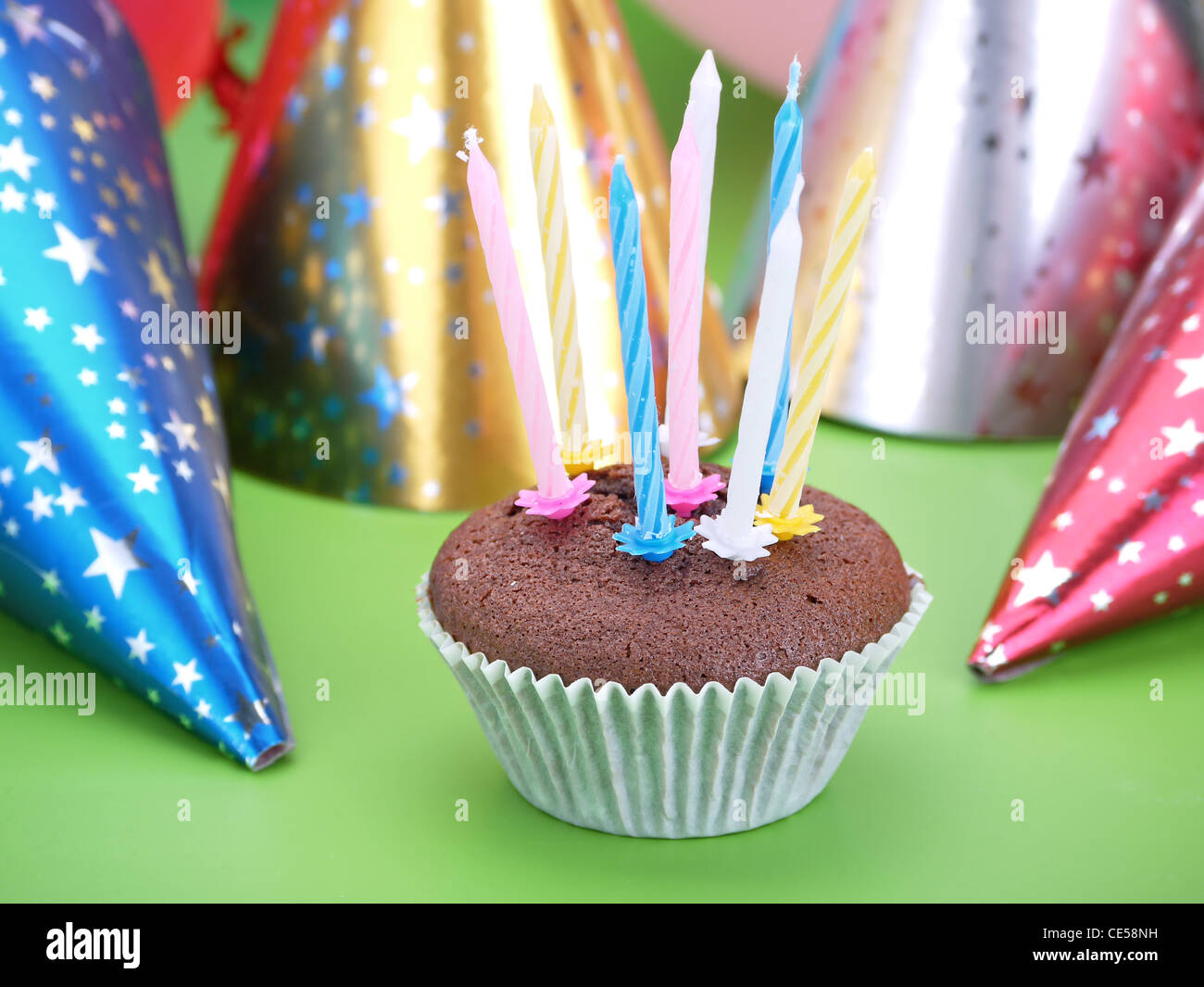 Muffin au chocolat décoré avec avec huit bougies cône parti caps dans l'arrière-plan Banque D'Images