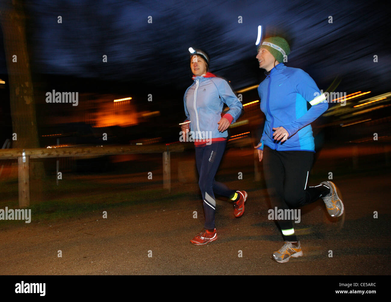 Deux jeunes femmes jogging la nuit en hiver, l'automne. Avec les projecteurs dans l'obscurité, sous l'étoffe. Banque D'Images