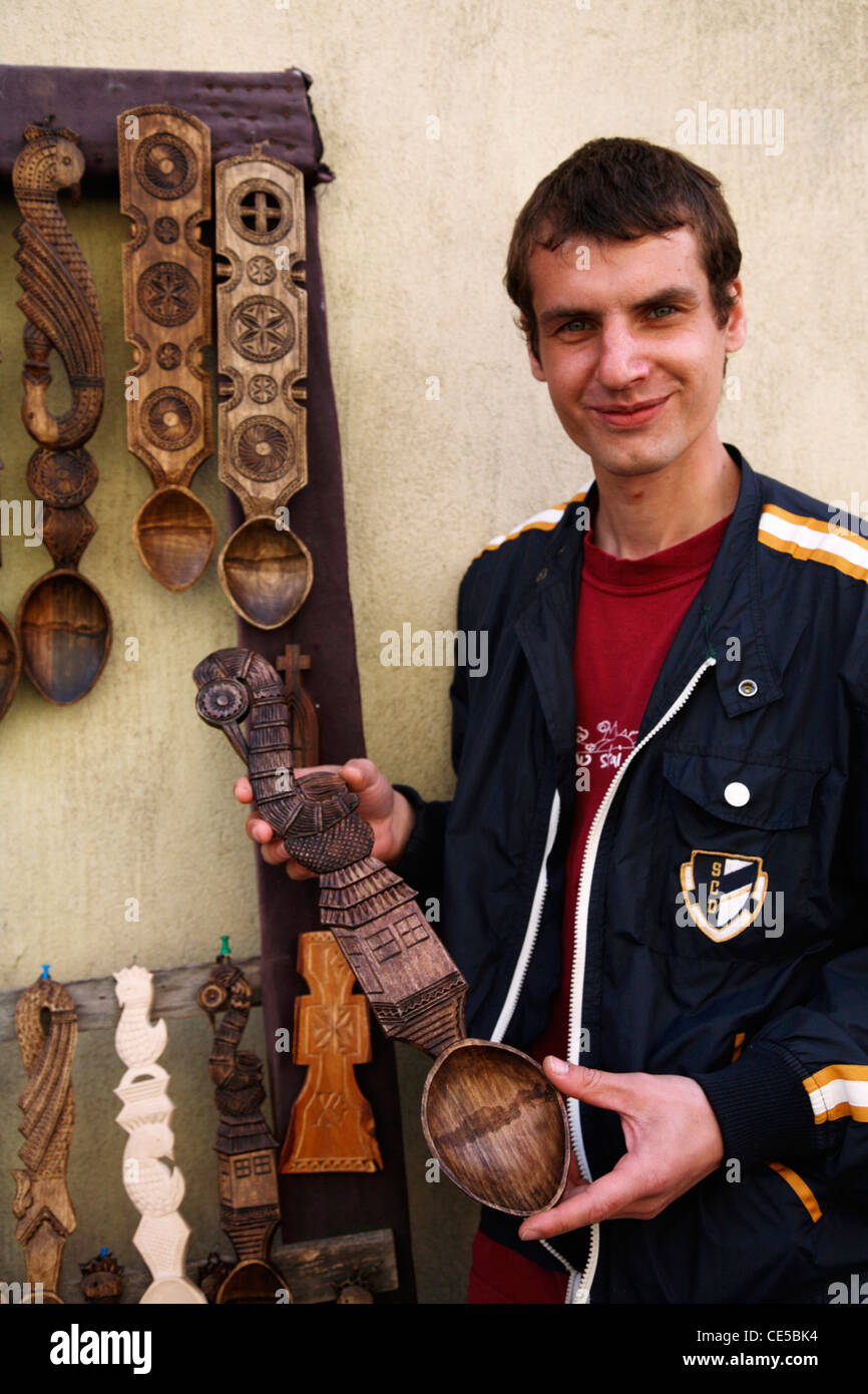 L'Europe, Roumanie, Sighisoara, un jeune homme la vente de bois sculpté cuillères en centre ville Banque D'Images
