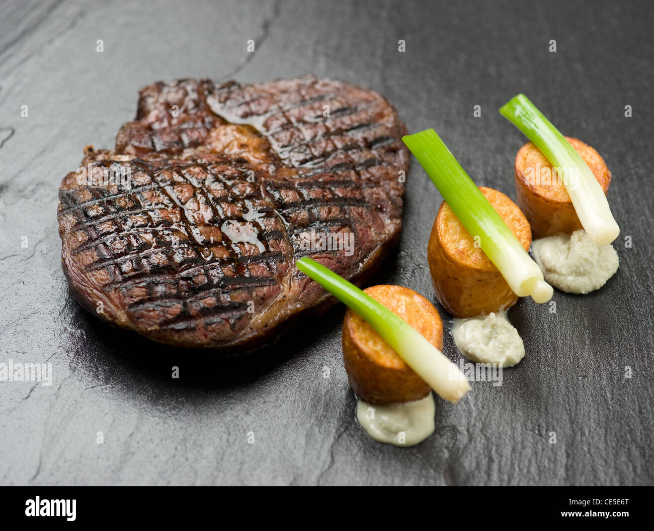 Un steak avec pommes de terre rôties et poireaux bébé Banque D'Images