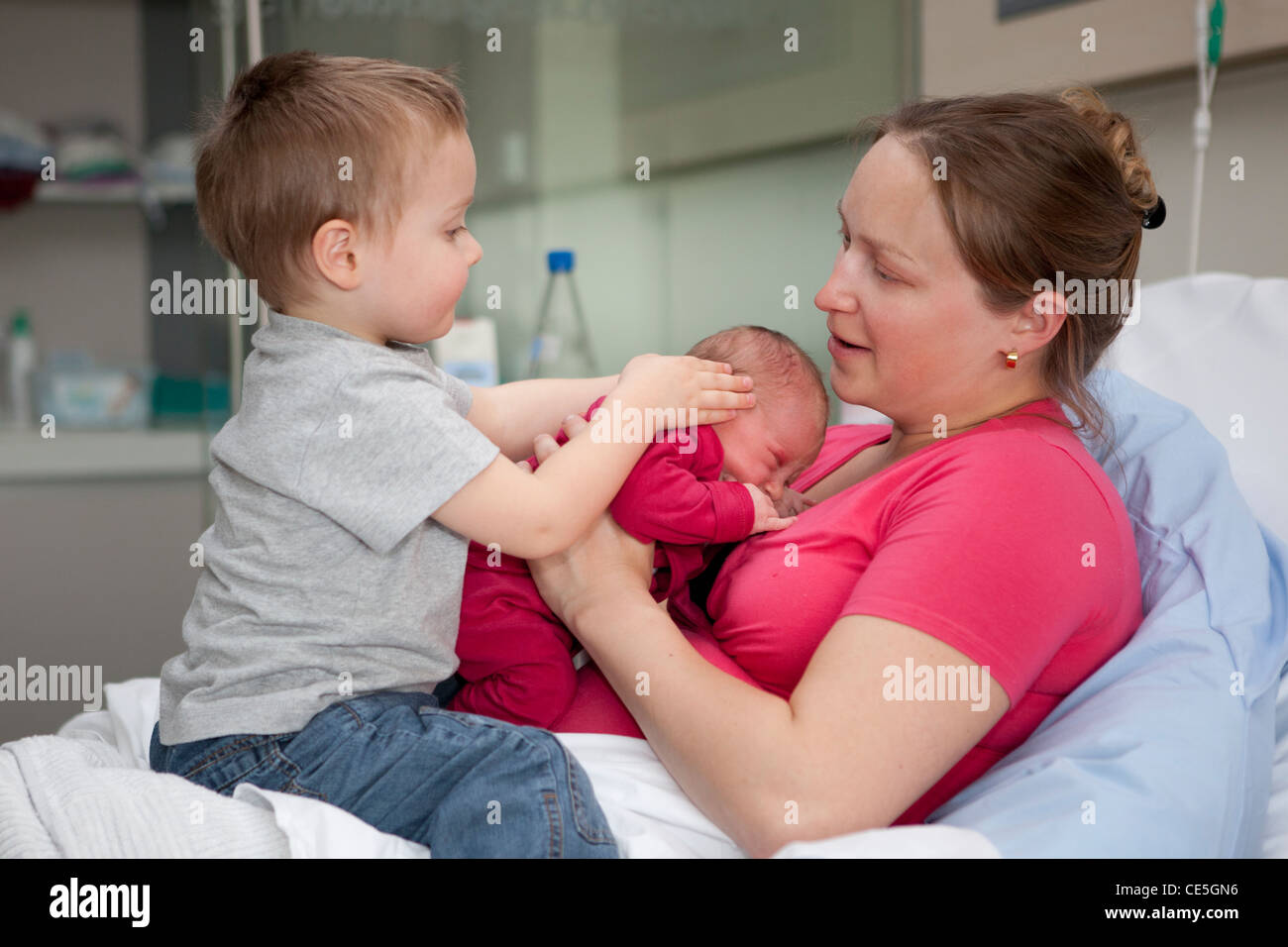 Une mère tient son nouveau-né fille alors que son fils est assis sur ses genoux à la maternité. Banque D'Images