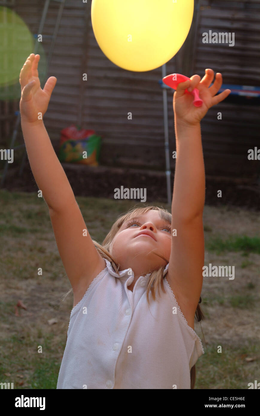Une petite fille de lancer un ballon en l'air Photo Stock - Alamy