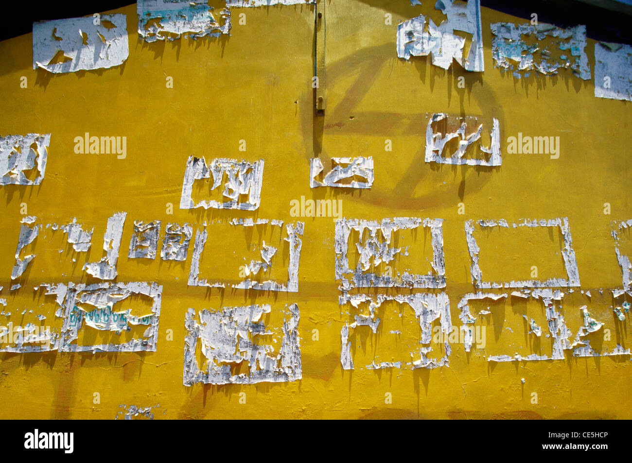 Affiches blanches déchirées sur le mur jaune ; Raghurajpur; Orissa ; Odisha ; Inde ; Asie Banque D'Images