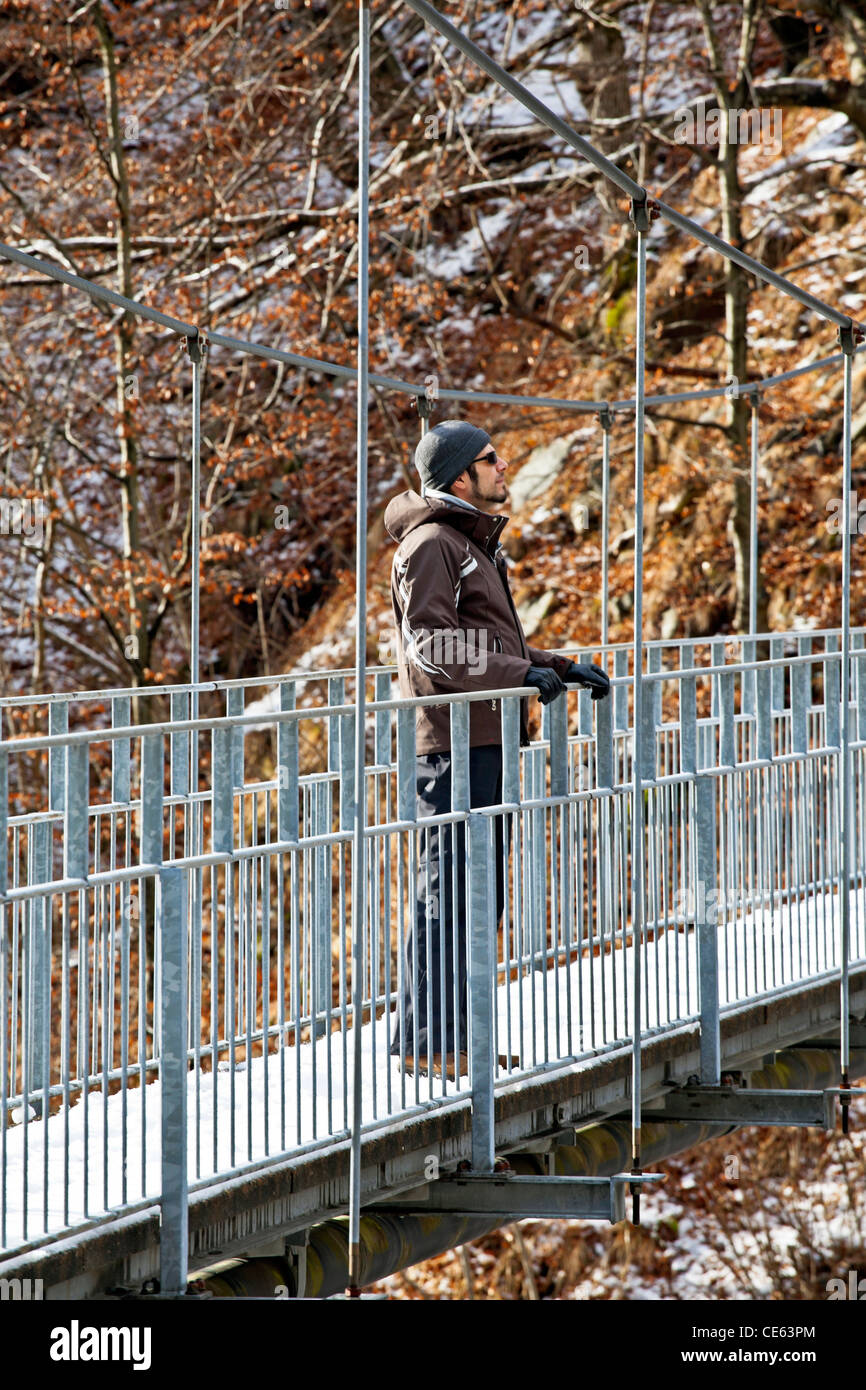 L'homme se tient sur un pont suspendu dans les montagnes de la Valle Onsernone, Tessin, Suisse et dans la distance Banque D'Images