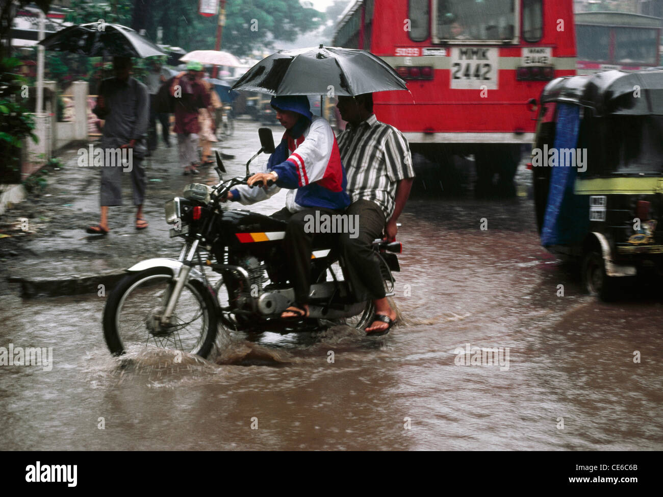 Les hommes avec parapluie noir ouvert le vélo dans la pluie de mousson ; les inondations ; Bombay Mumbai maharashtra Inde ; Banque D'Images