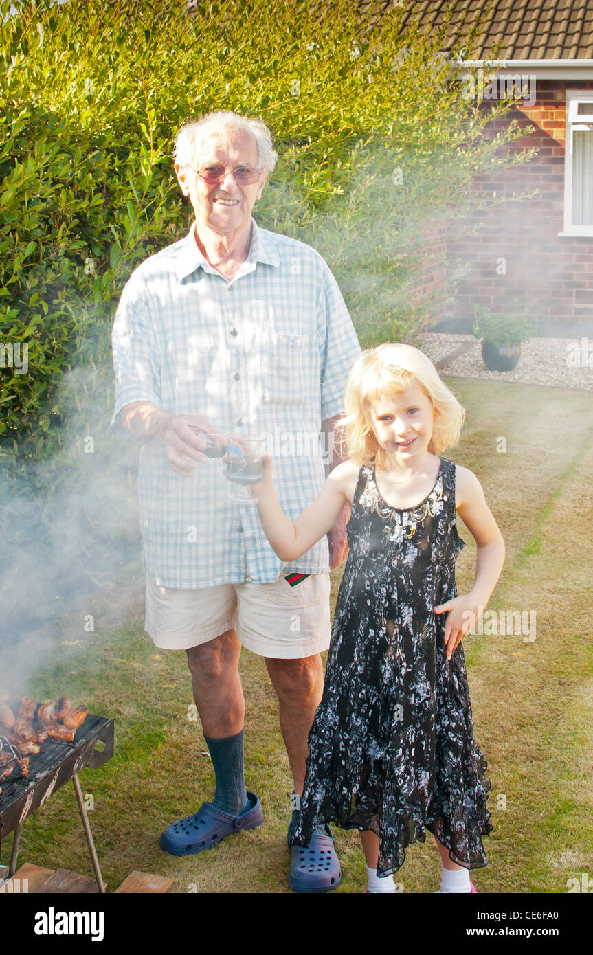 Jardin Barbecue familial Blackpool England uk europe la cuisson de la viande barbecue en plein air jeune femme fumée fumée smokey eyes de la fumée dans les yeux Banque D'Images