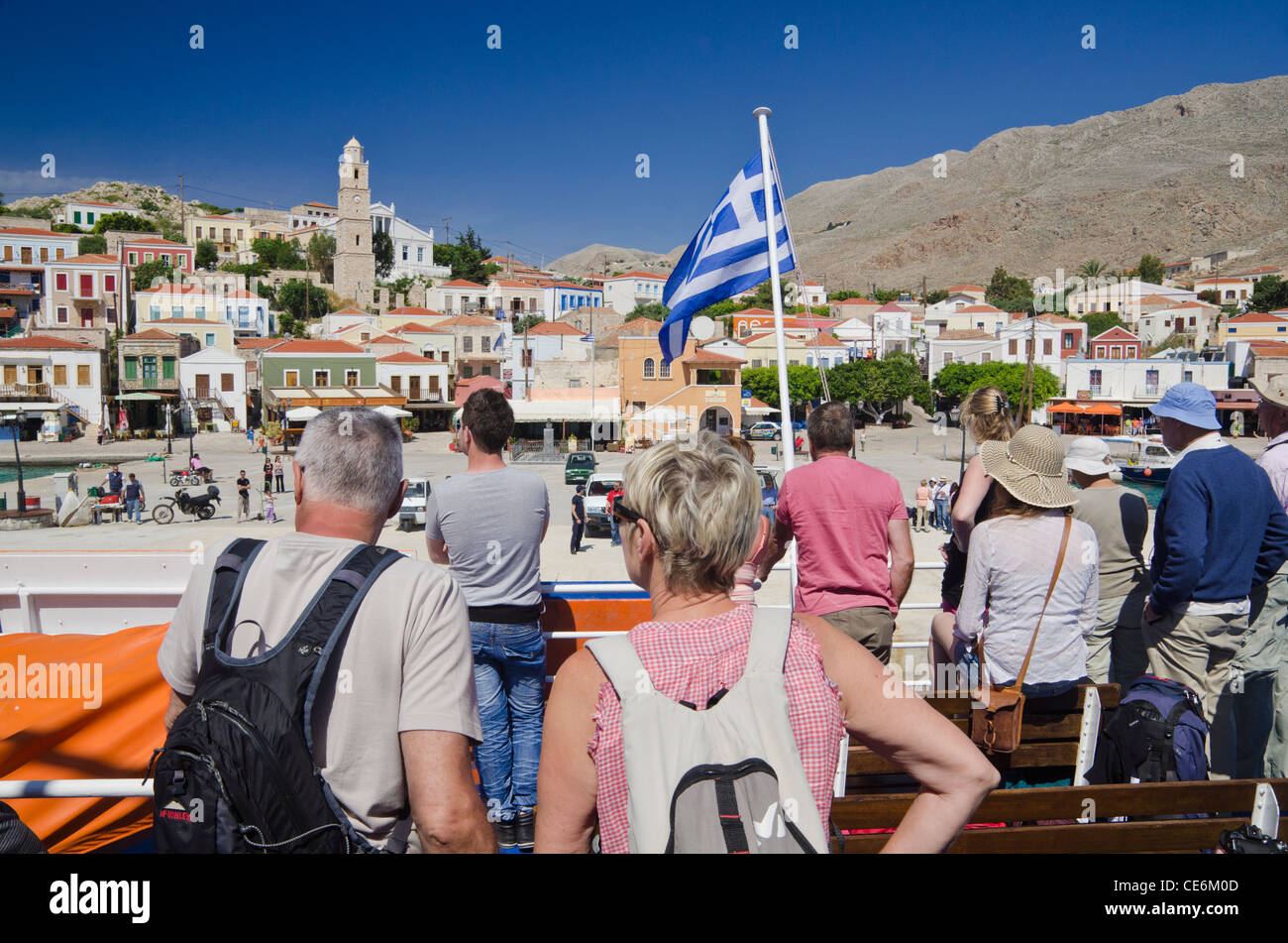 Les voyageurs profitant de la vue depuis le pont d'un ferry à mesure qu'il arrive dans la ville portuaire de l'île de Halki Emborios, Grèce Banque D'Images