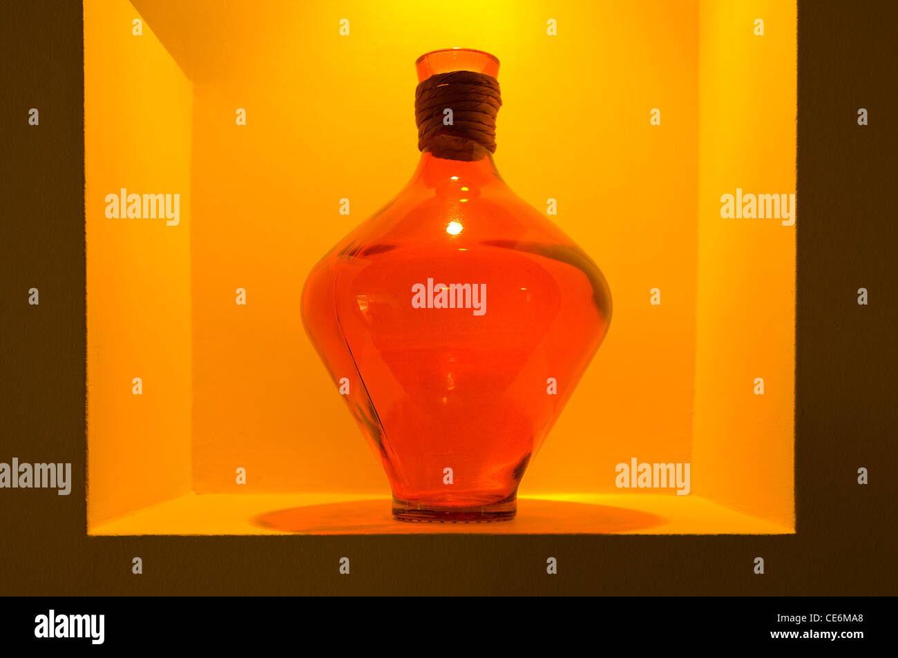 Vase en verre encadrée par découpe mur orange sous spotlight Banque D'Images