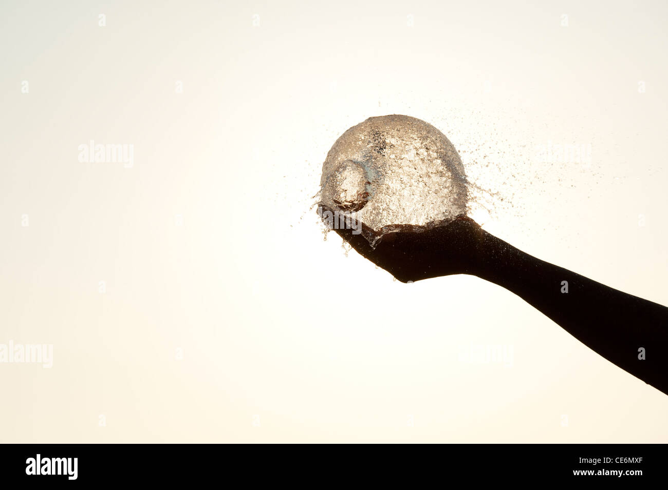 Silhouette ronde main tenant un ballon d'eau éclatent Banque D'Images