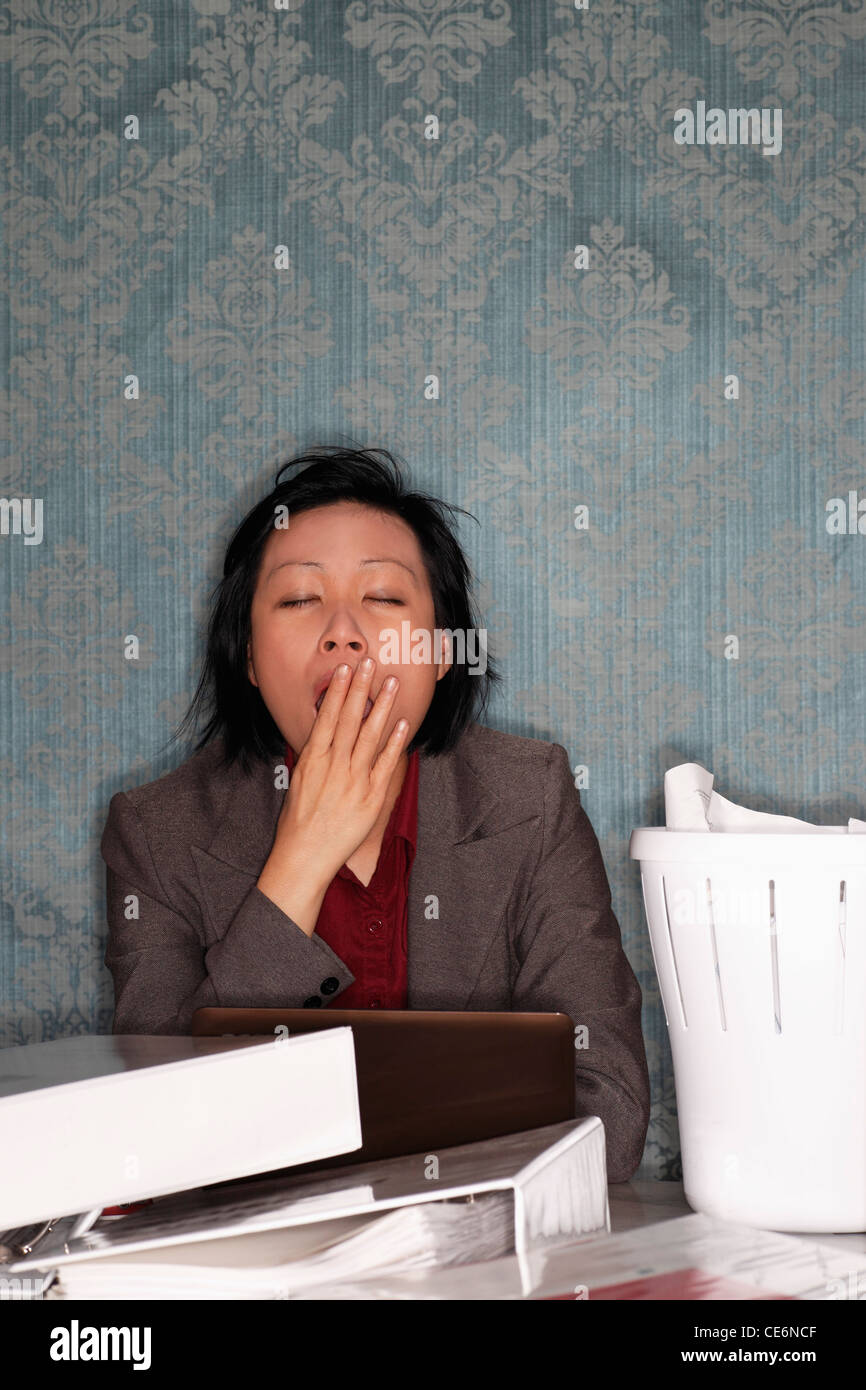Chinese woman sitting at bureau malpropre le bâillement Banque D'Images