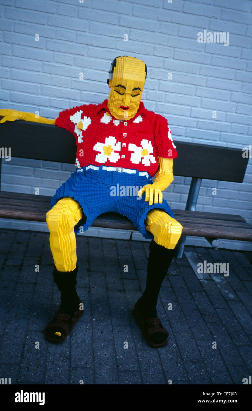 Sculpture Lego à grande échelle d'un homme avec un shirtr hawaïen rouge s'élaxant sur un banc de parc dans le parc Legoland près de Billund Danemark Banque D'Images