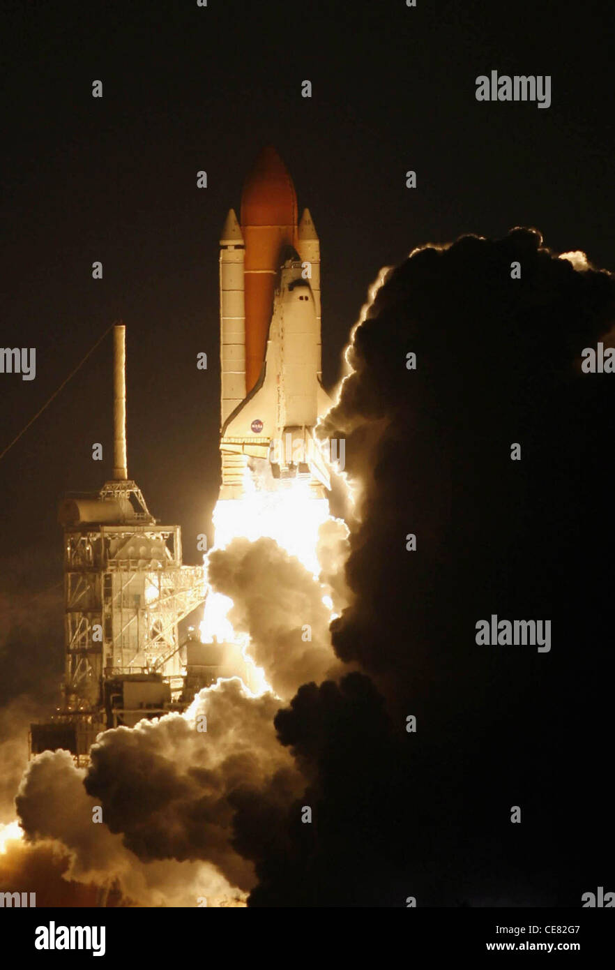 Depuis la fumée et la vapeur, Space Shuttle Discovery se lance dans le ciel, à côté du mât de la foudre sur Launch Pad 39B au Kennedy Space Center le 9 décembre à 8 h 47 (HNE). La 45e Escadre spatiale de la Force aérienne, sortie de la base aérienne Patrick, en Floride, a soutenu le premier lancement nocturne de la NASA en quatre ans. Banque D'Images