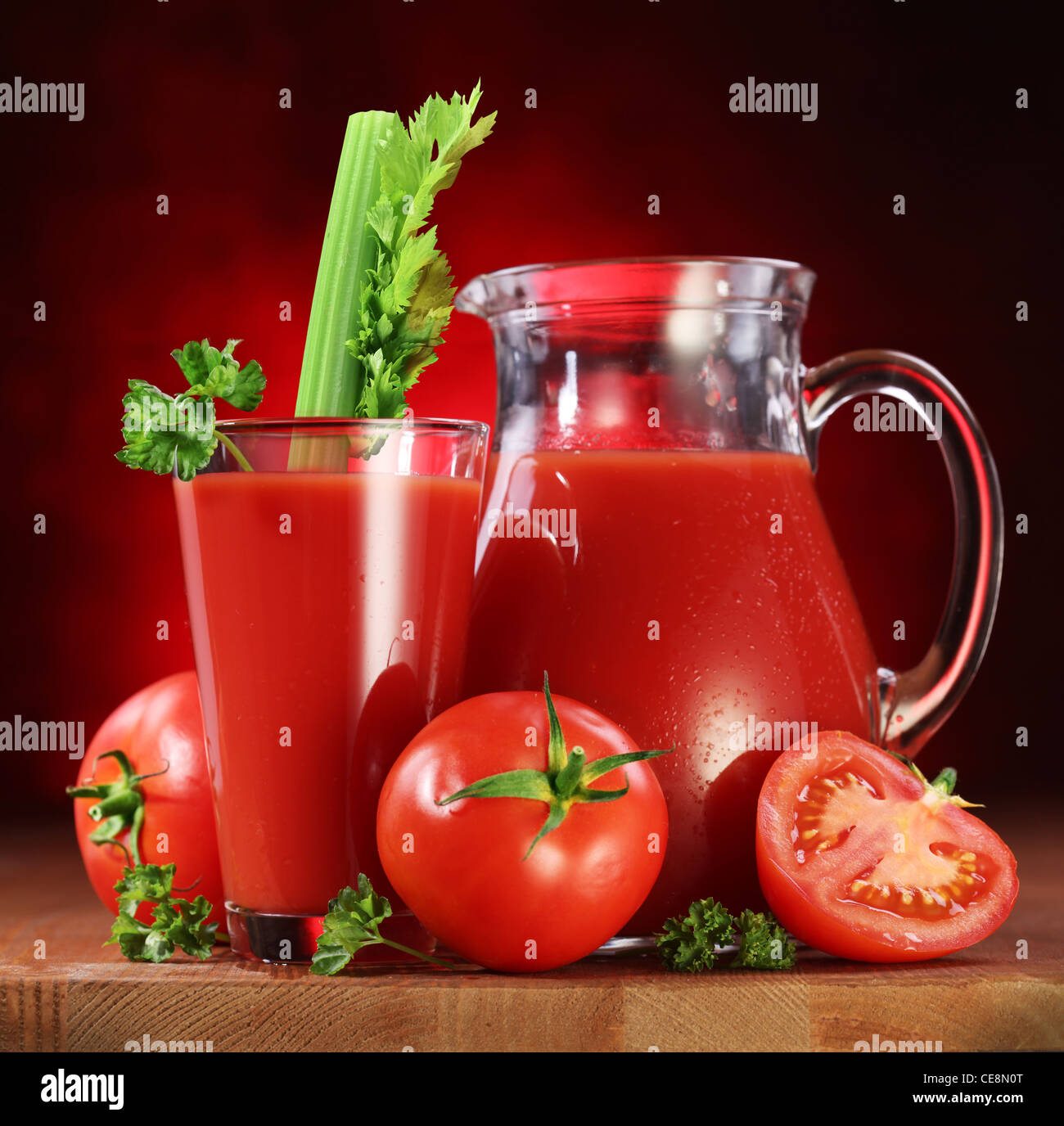 Still Life : tomates, verseuse en verre et plein de jus de tomates fraîches sur la table en bois. Banque D'Images