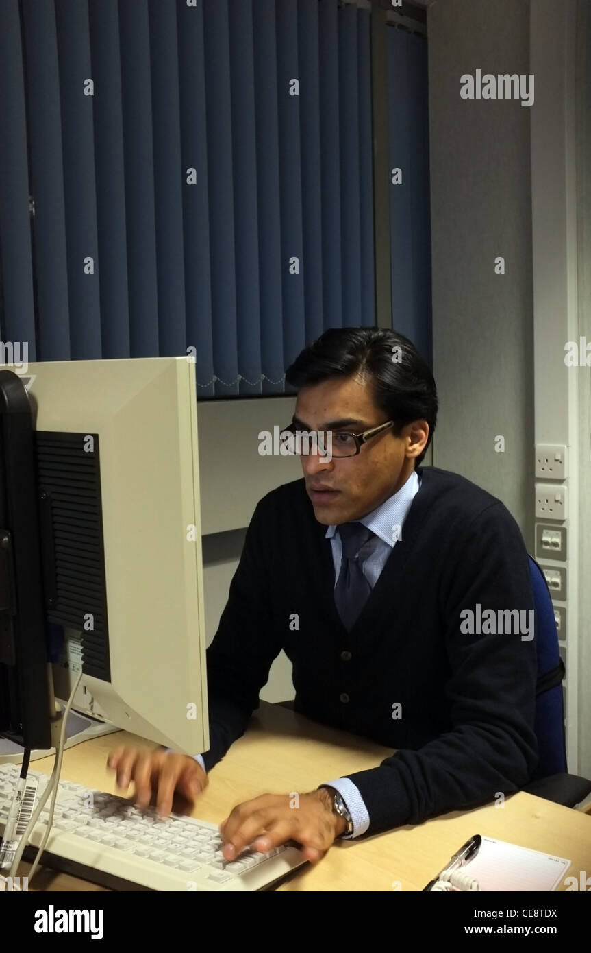 Un homme assis à l'ordinateur de bureau en bureau contemporain. Banque D'Images