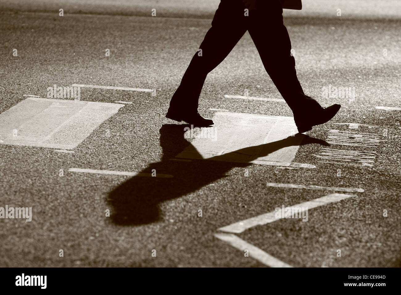 Les jambes d'un homme tel qu'il traverse une route à un passage piétons à Londres Banque D'Images