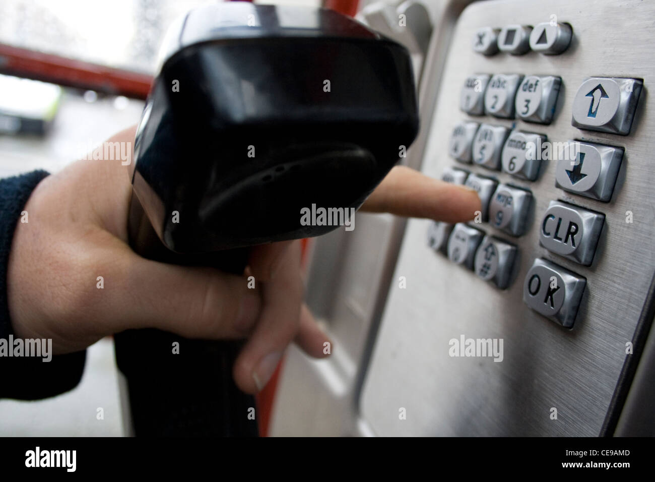 Une personne dans une cabine téléphonique à l'aide du clavier téléphonique. Banque D'Images