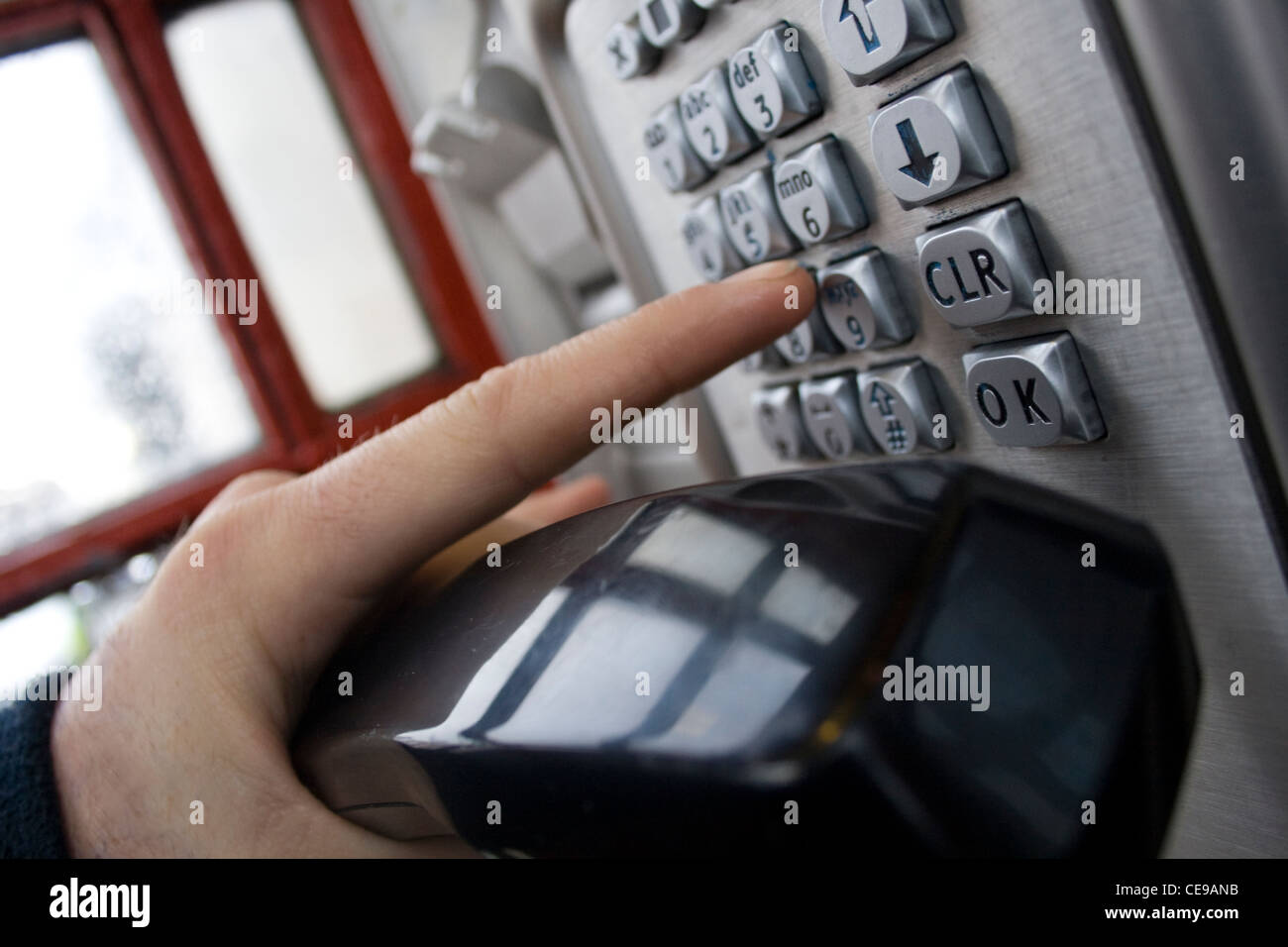 Une personne dans une cabine téléphonique à l'aide du clavier téléphonique. Banque D'Images