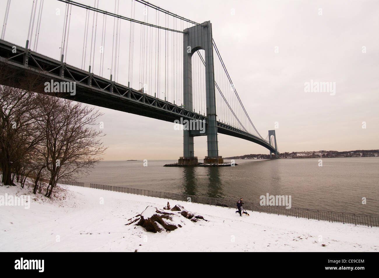 La neige recouvre le sol sur le côté de Brooklyn du Verrazano-Narrows Bridge car les gens en-dessous avec jog leur chien. Banque D'Images