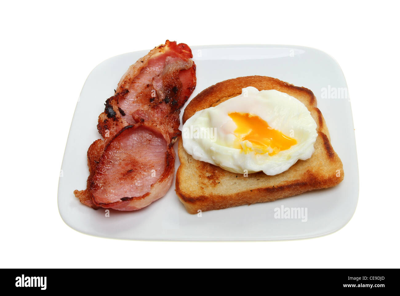L'œuf poché avec un écoulement jaune sur pain frit avec du bacon dans une assiette blanche contre isolés Banque D'Images L'œuf poché avec un écoulement jaune sur pain frit avec du bacon dans une assiette blanche contre isolés Banque D'Images