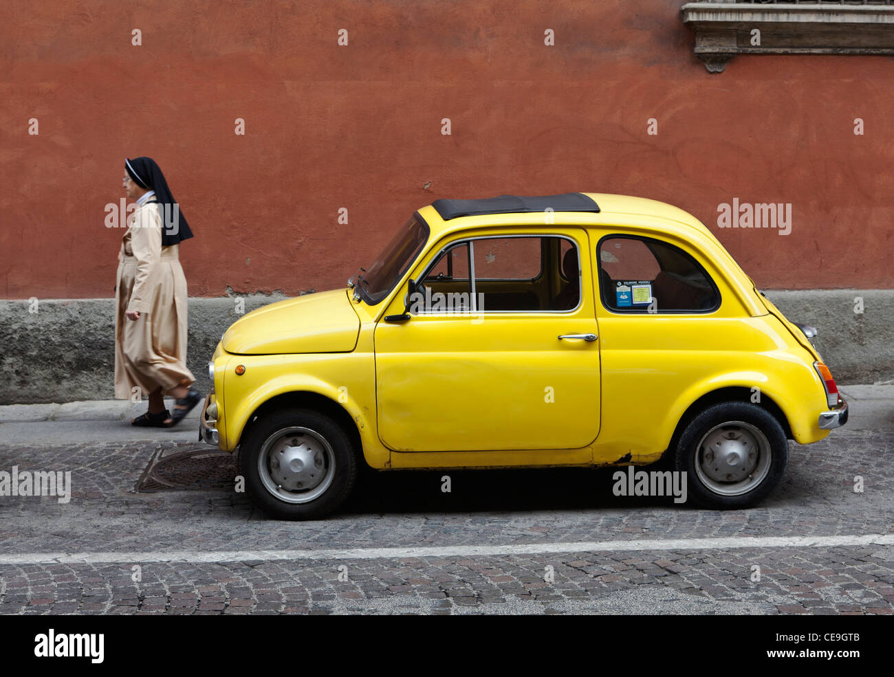 Une nonne passe une Fiat 500 jaune Piemonte Italie Banque D'Images