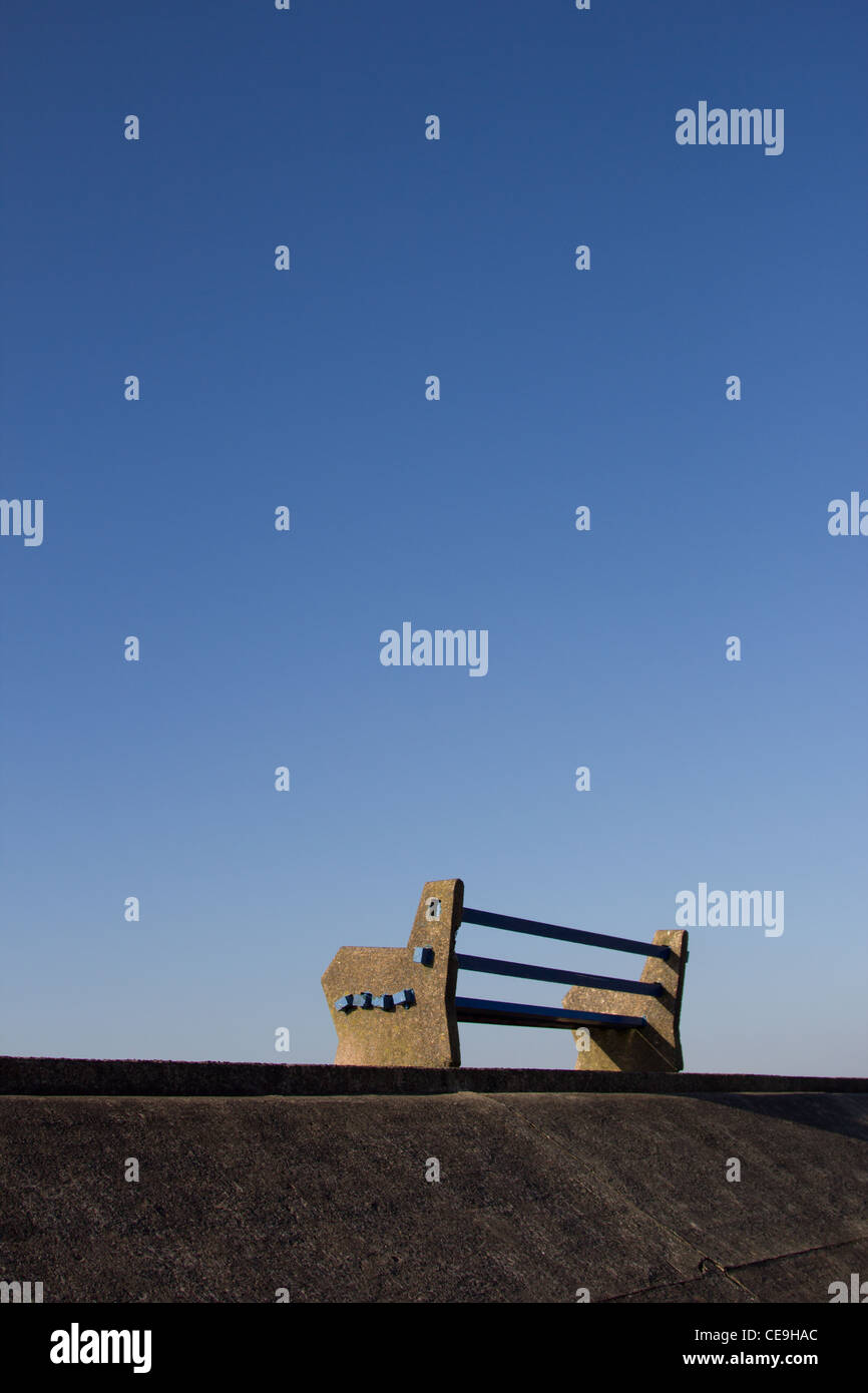 Banc vide sur la promenade de Borth, Pays de Galles, sur un jour d'hiver bleu clair Banque D'Images