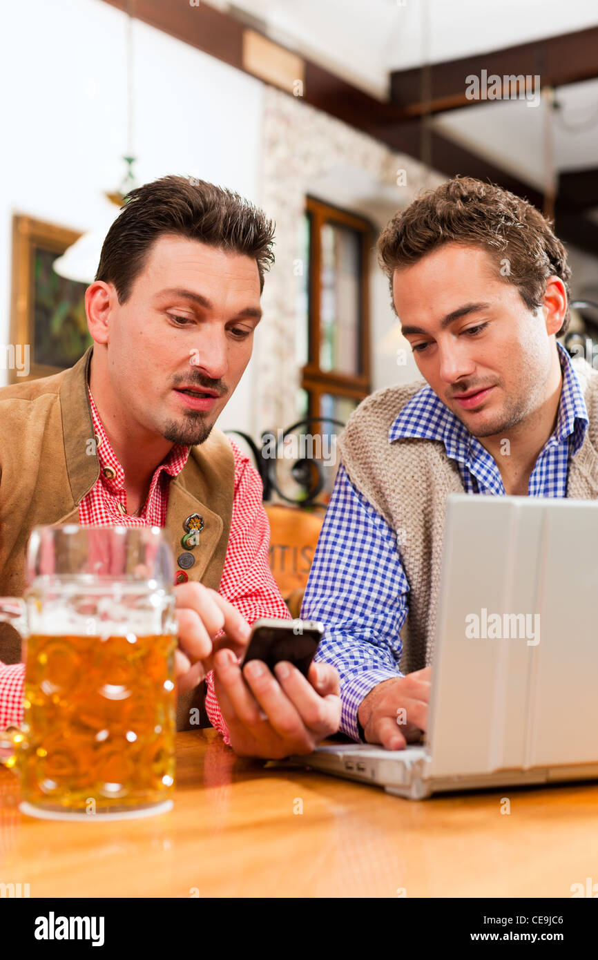 Deux amis en pub bavarois en vêtements traditionnels assis sur une table dans un pub avec coffre Banque D'Images