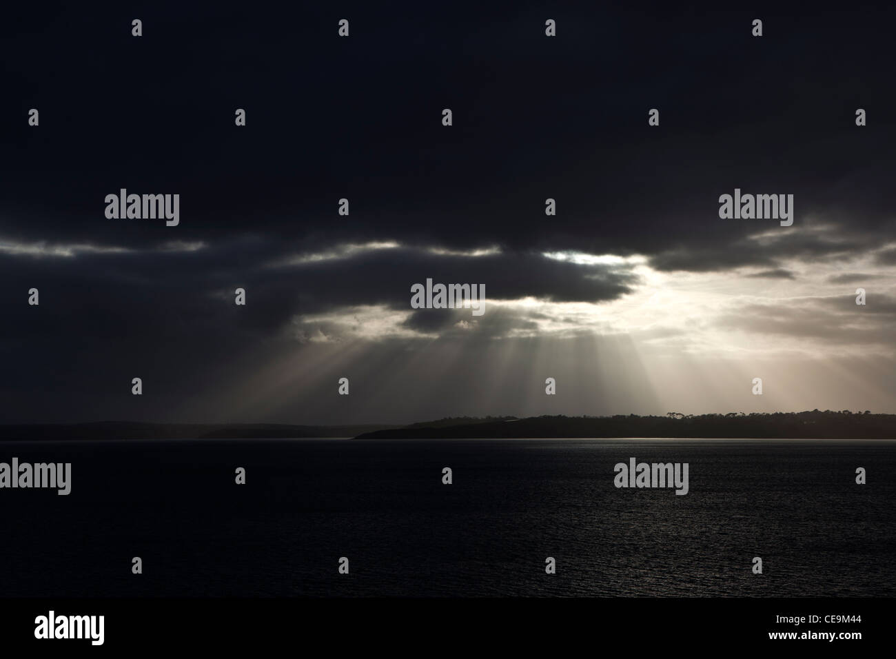 Un nuage éclaté à travers un ciel dramatique moody à Falmouth Bay sur la péninsule de Lizard. Banque D'Images