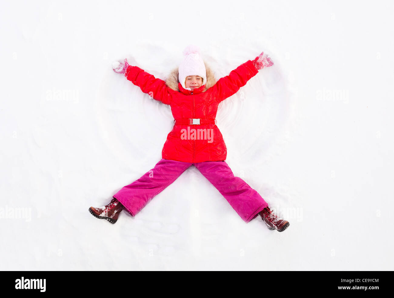 Jeune fille portant sur le terrain Making Snow Angel Banque D'Images