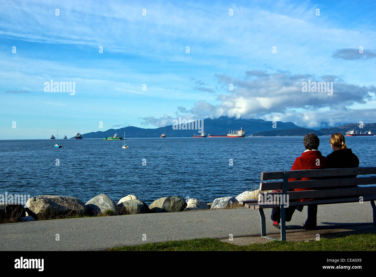 Deux femmes assises banc de parc Vanier Park à cargos ancrés English Bay Banque D'Images