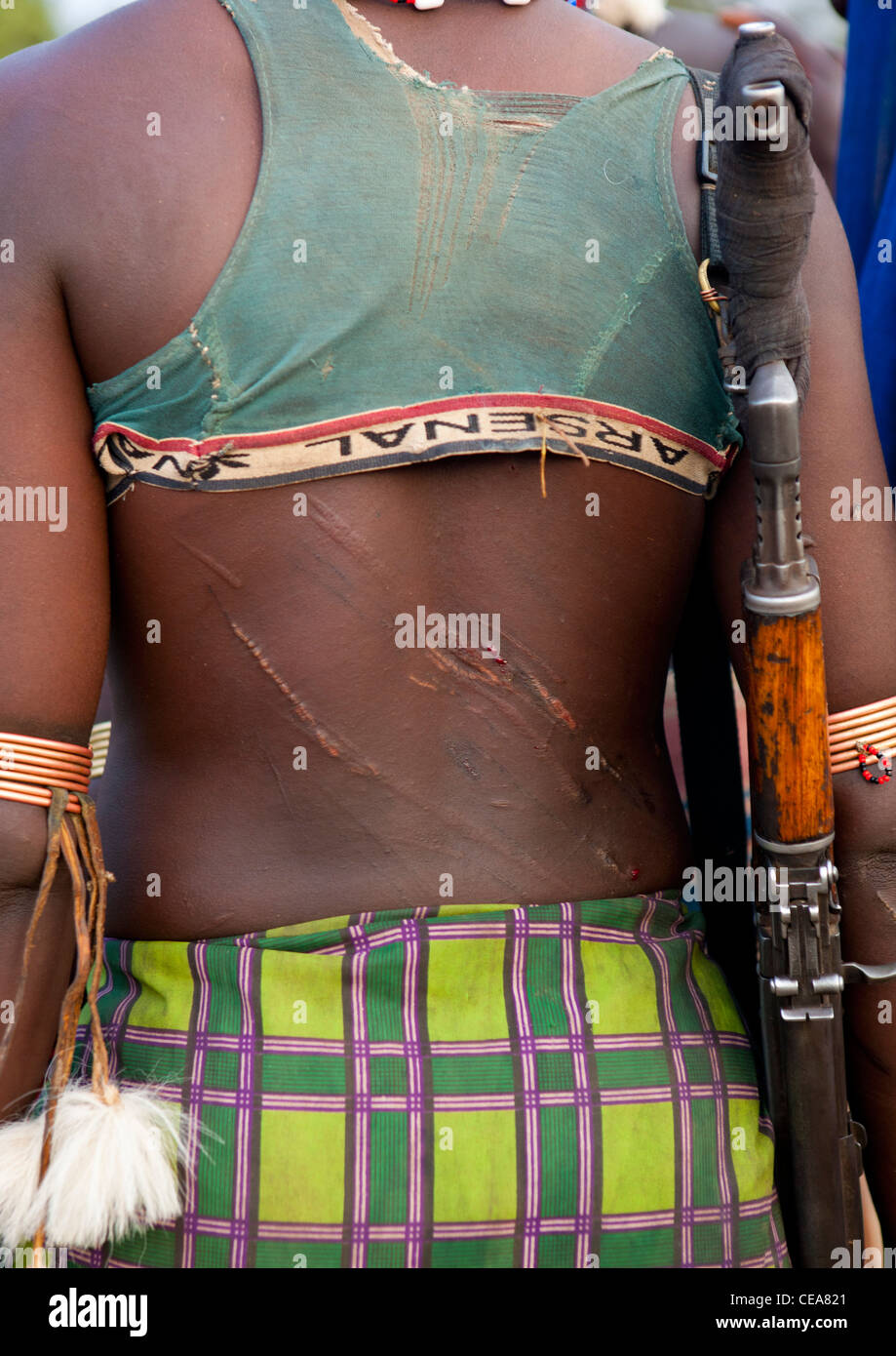 Dos de Femme Banna flagellées précédemment portant Kalachnikov Bull Cérémonie Vallée de l'Omo Ethiopie Saut Banque D'Images
