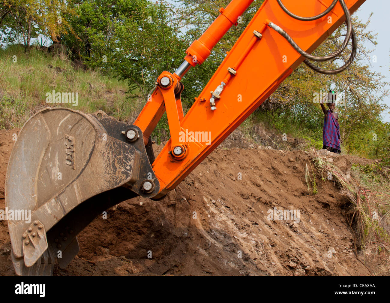 Femme autochtone et Mechanical Digger Arm sur la construction de routes revêtues travailler dans le parc Mago Vallée de l'Omo en Ethiopie Banque D'Images