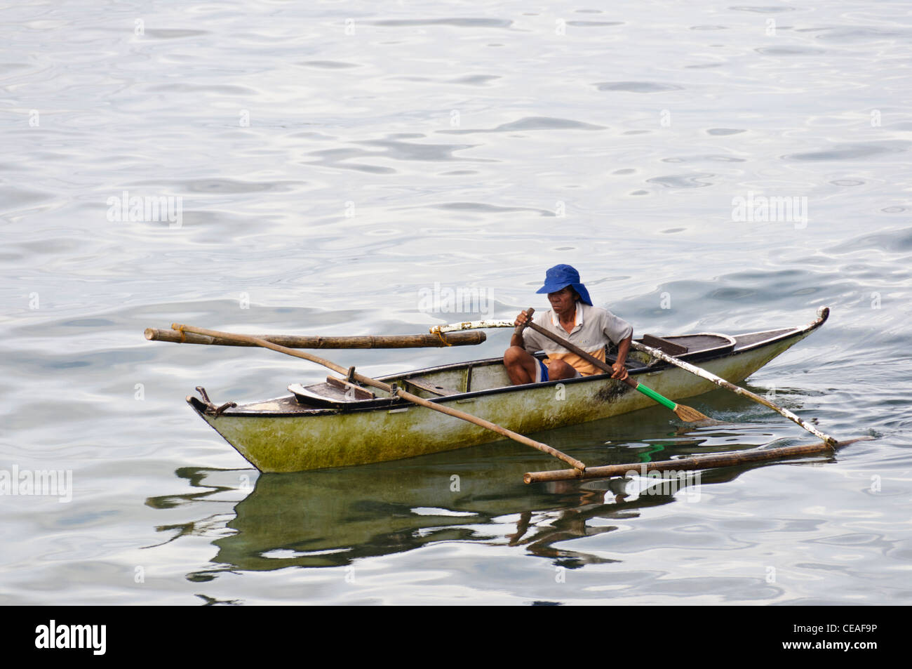 Old Asian man avec capuchon bleu l'aviron un petit bateau outrigger  philippin, également appelé banca ou banka dans l'océan Photo Stock - Alamy