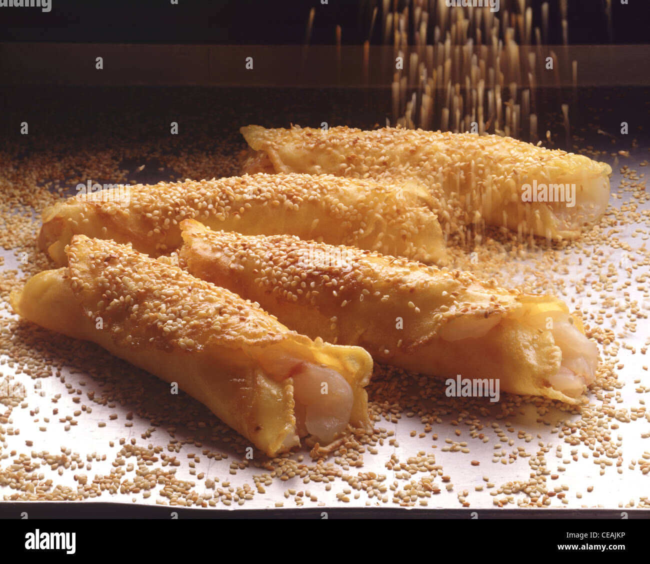 Filet de baudroie enveloppés de crêpes étant couvert de graines de sésame Banque D'Images