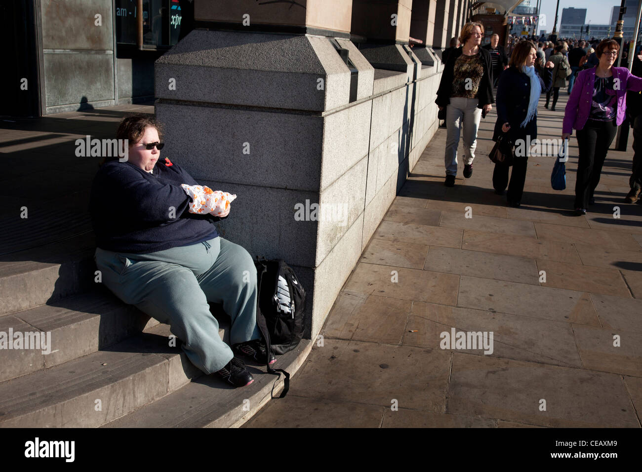 Grande Femme assise eating fast food. Banque D'Images