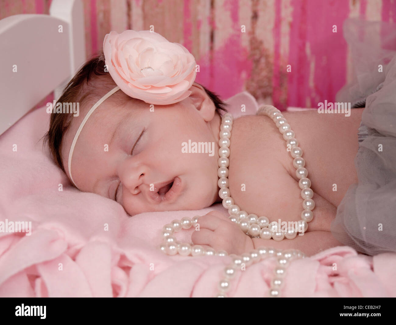 Gros plan du nouveau-né une belle petite fille aux fleurs rose, gris bandeau tutu, et de perles, elle est profondément endormie. Banque D'Images