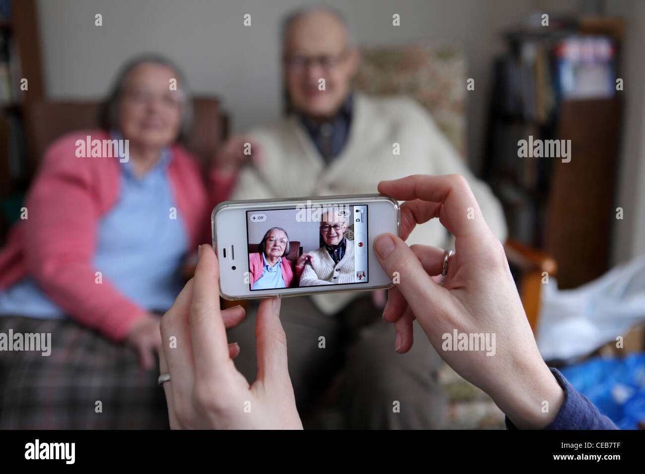À l'aide d'un iPhone 4S pour prendre des photos de famille à la maison, des générations différentes en utilisant la technologie d'écran tactile intuitive, UK Banque D'Images