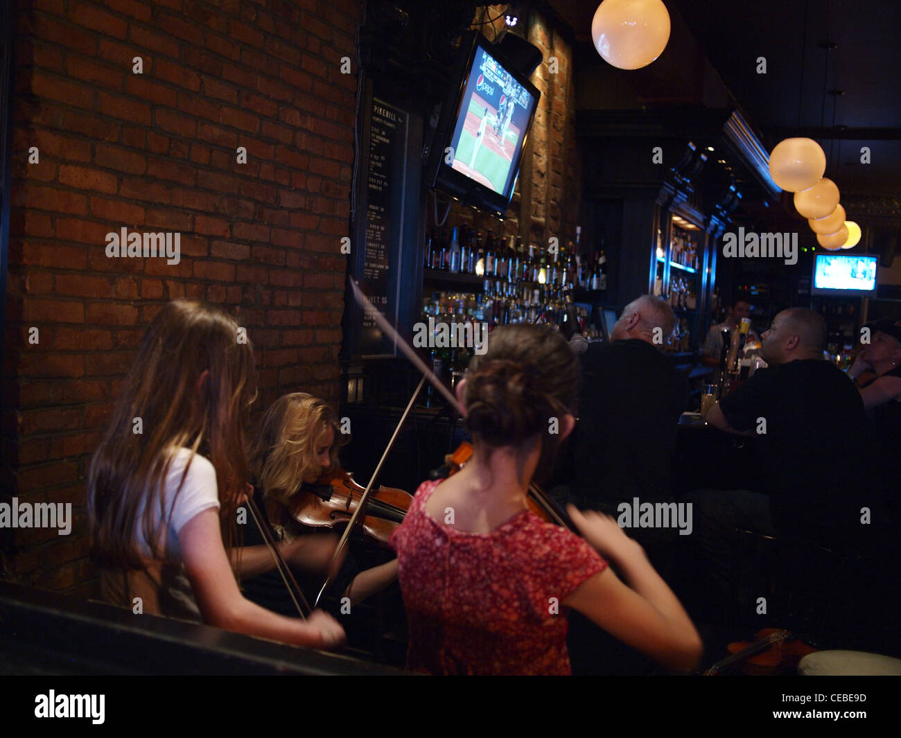 Musiciens jouant des airs de violoneux irlandais à Spike Bar Hill, Brooklyn, New York, en tant que clients regarder le baseball à la télévision Banque D'Images